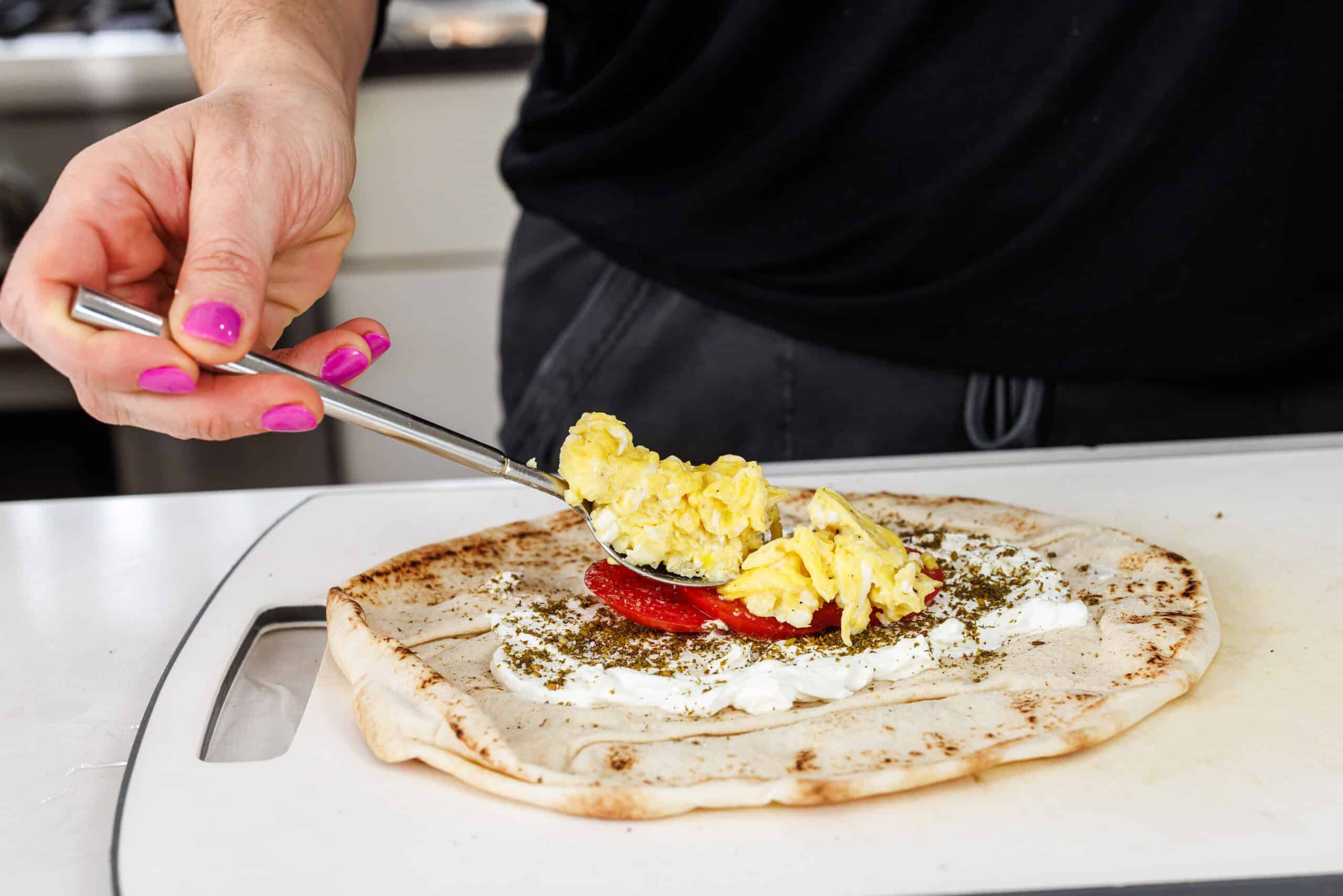 Adding scrambled eggs to breakfast pita.