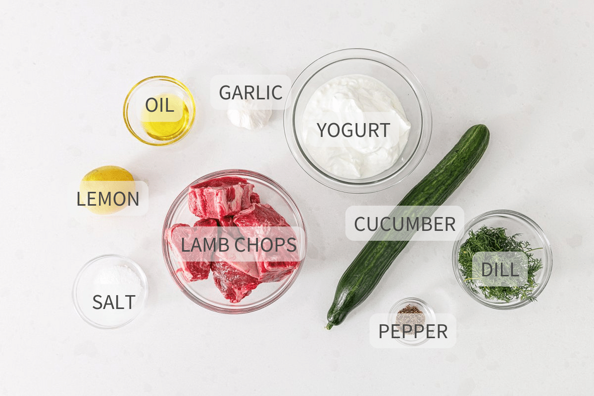 Labeled ingredients for greek lamb chops with tzatziki sauce on a white background.