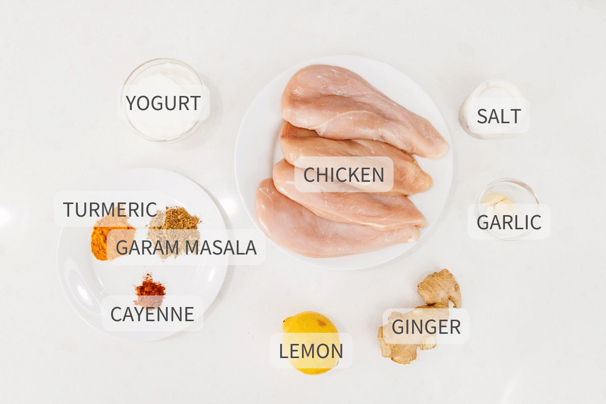 Labeled ingredients for grilled chicken recipe on a white backdrop.