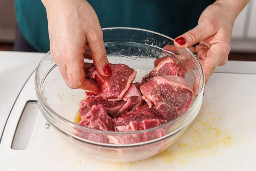 Seasoning lamb chops with salt and pepper in oil.