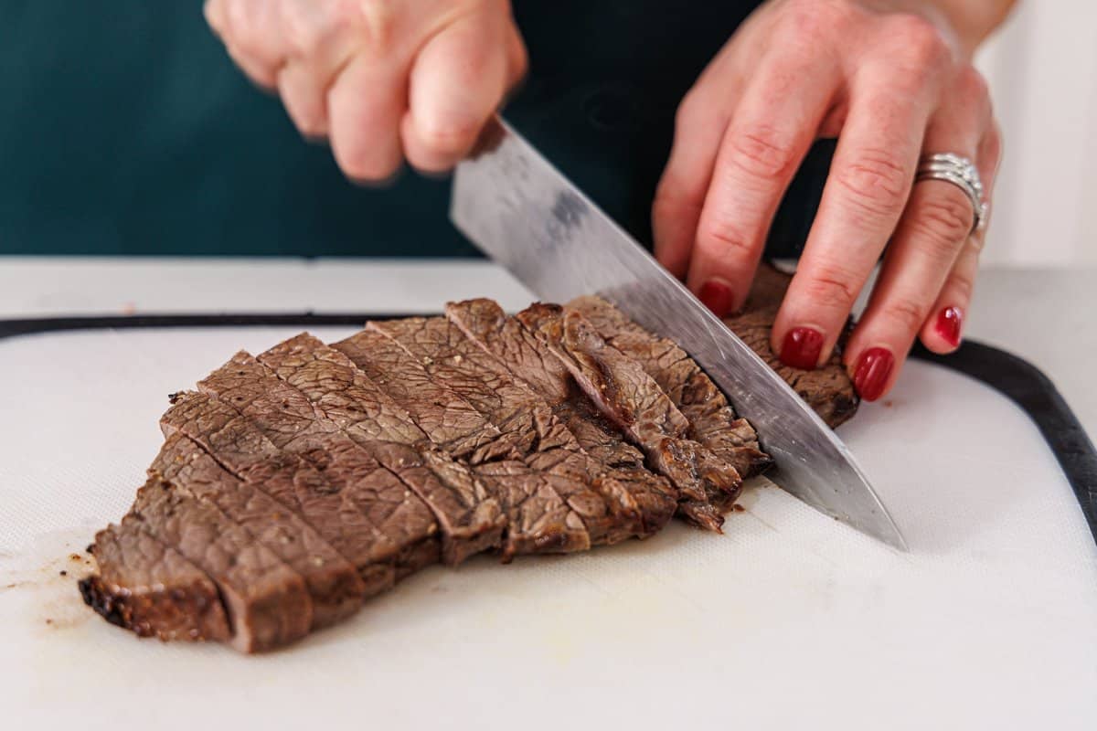 Slicing cooked sirloin against the grain.