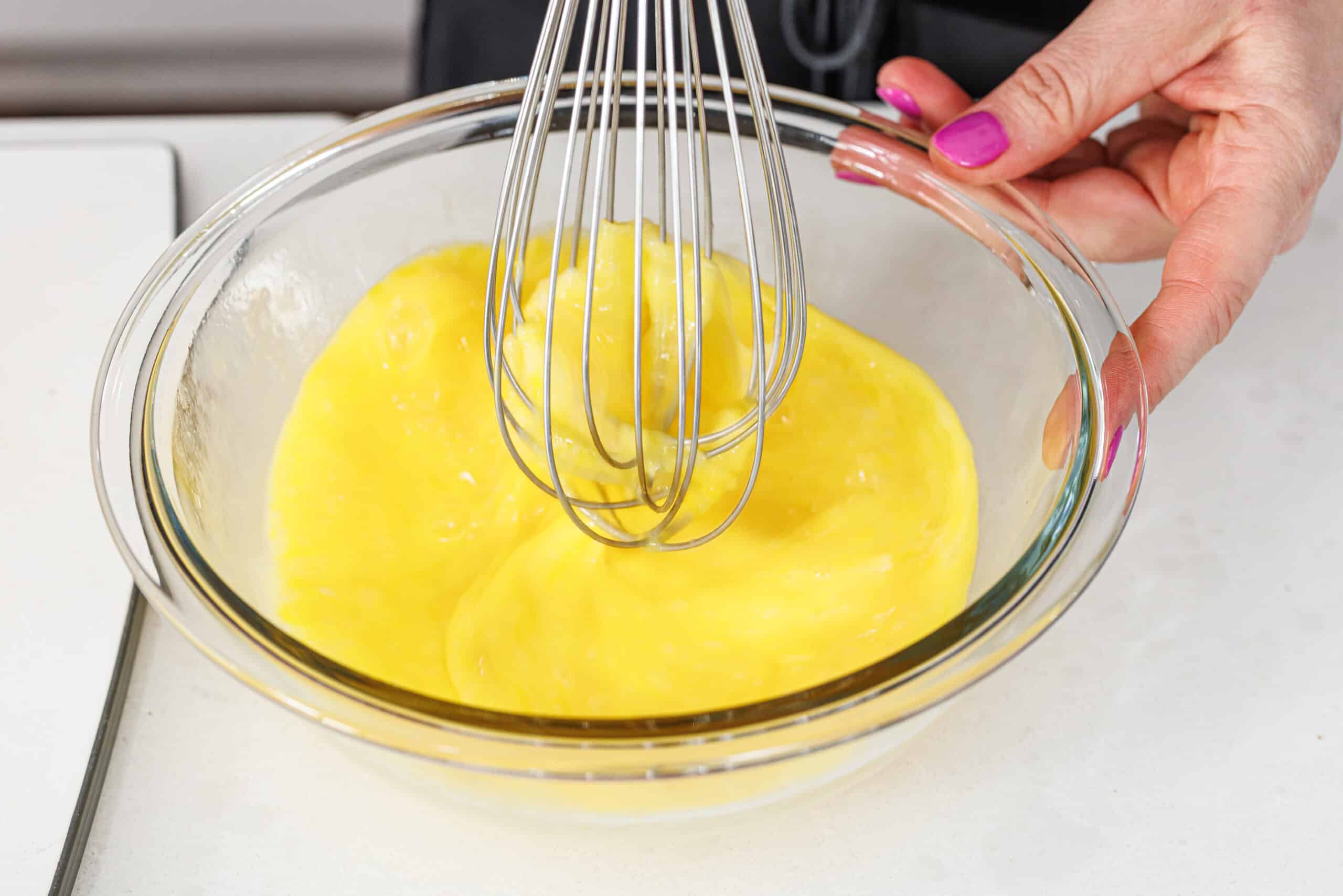 Whisking eggs in a large glass bowl.