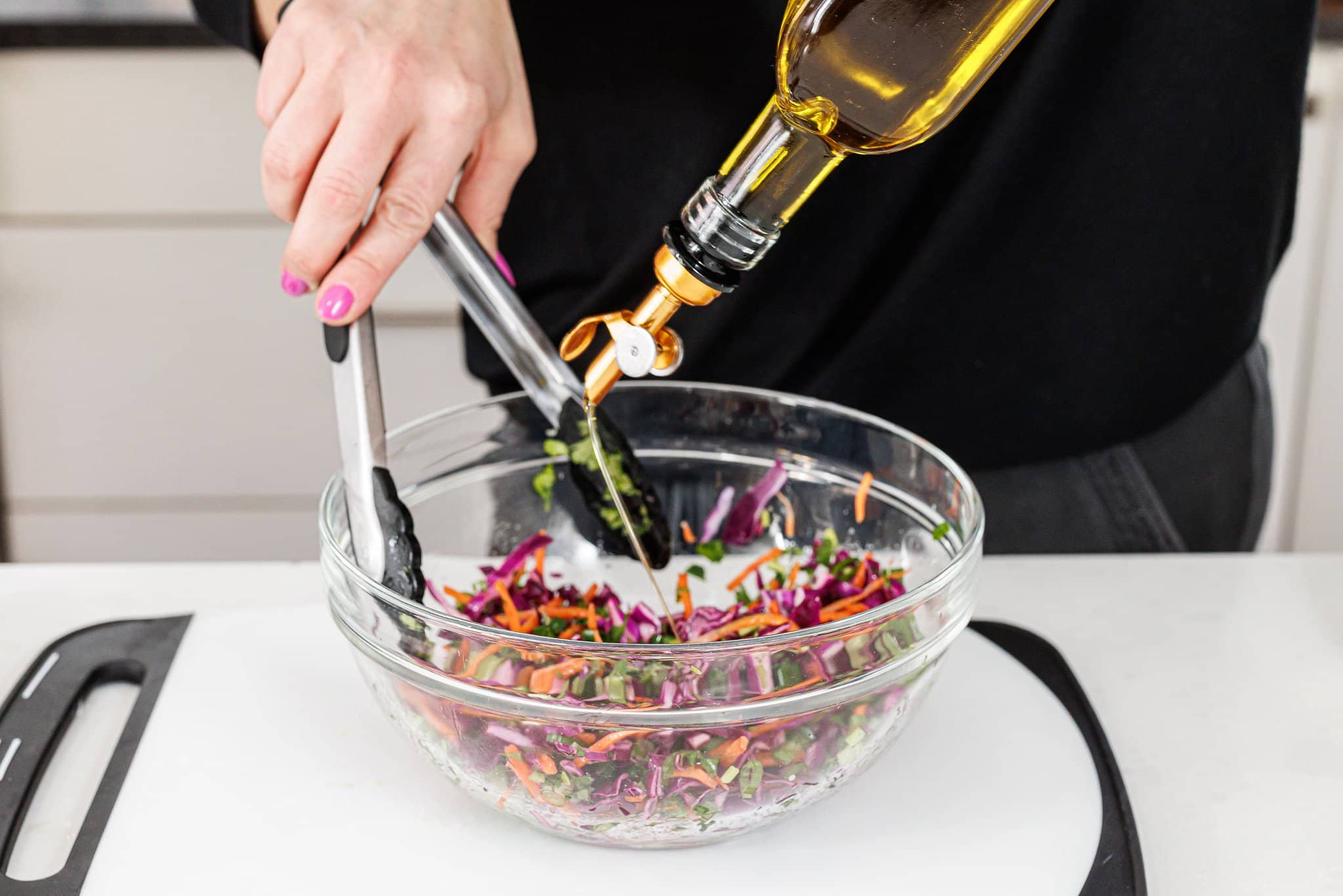 Drizzling olive oil over cabbage slaw.
