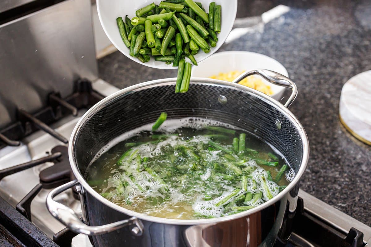 Adding green beans to boiling water.