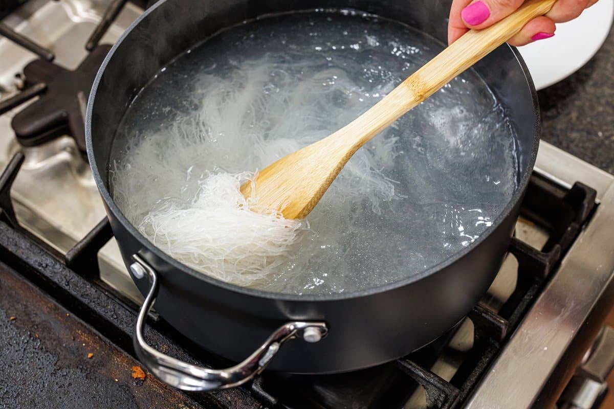 Cooking rice noodles in a large pot of boiling water.