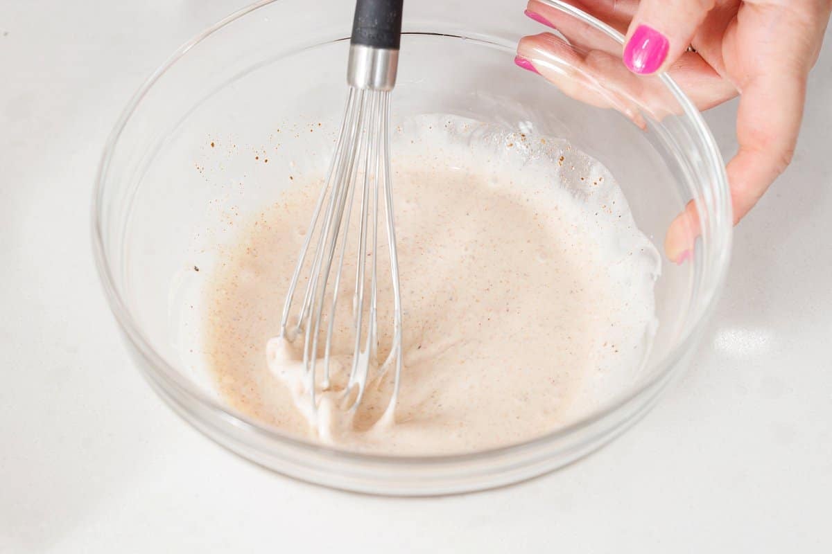 Whisking dressing for shrimp salad in a glass bowl.