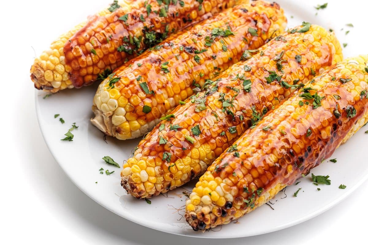 Healthy barbecue recipes, grilled corn on the cob with bbq sauce.