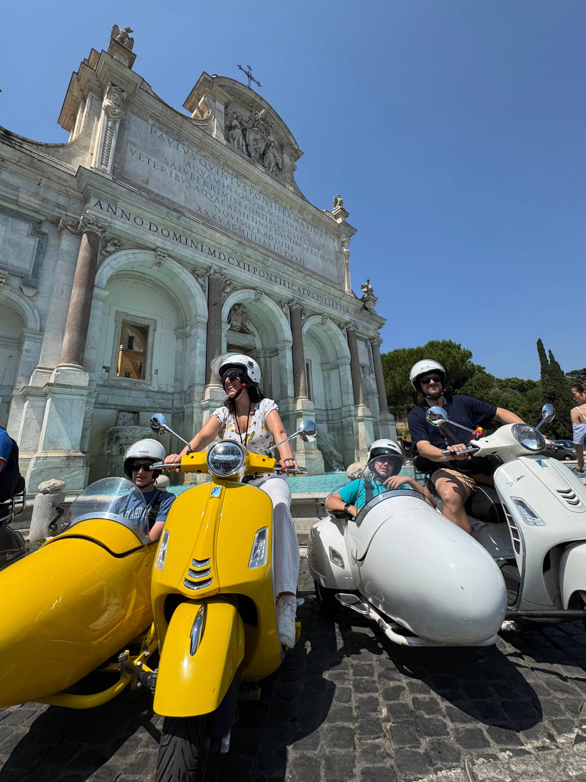 Liz and family sitting on vespas and in sidecars on the streets of Rome.