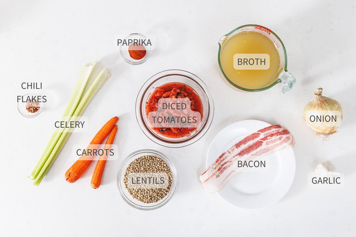 Labeled ingredients for slow cooker lentil soup with bacon on a white counter.