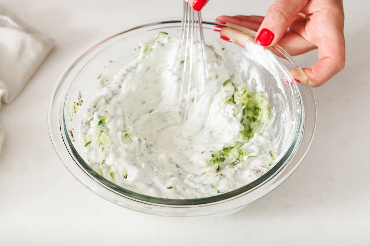 Whisking cucumber into yogurt.