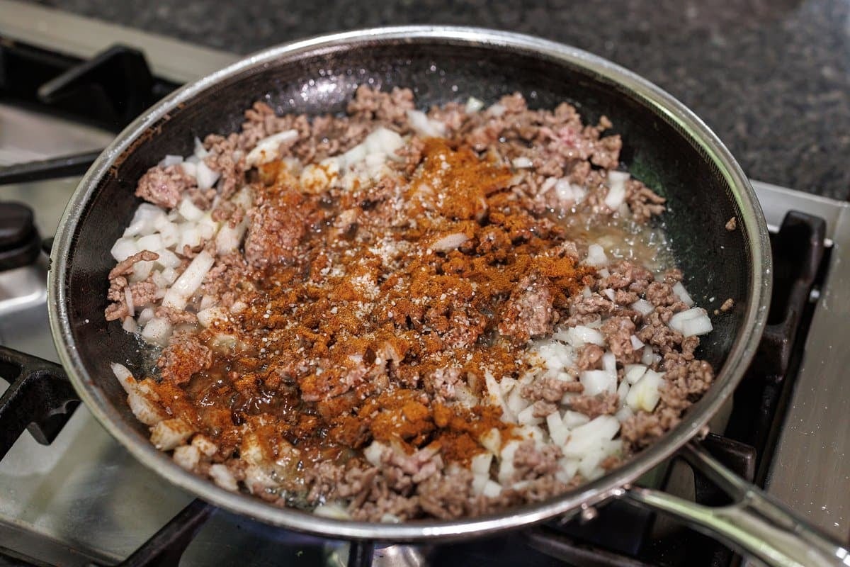 Adding spice blend and onion to ground lamb.