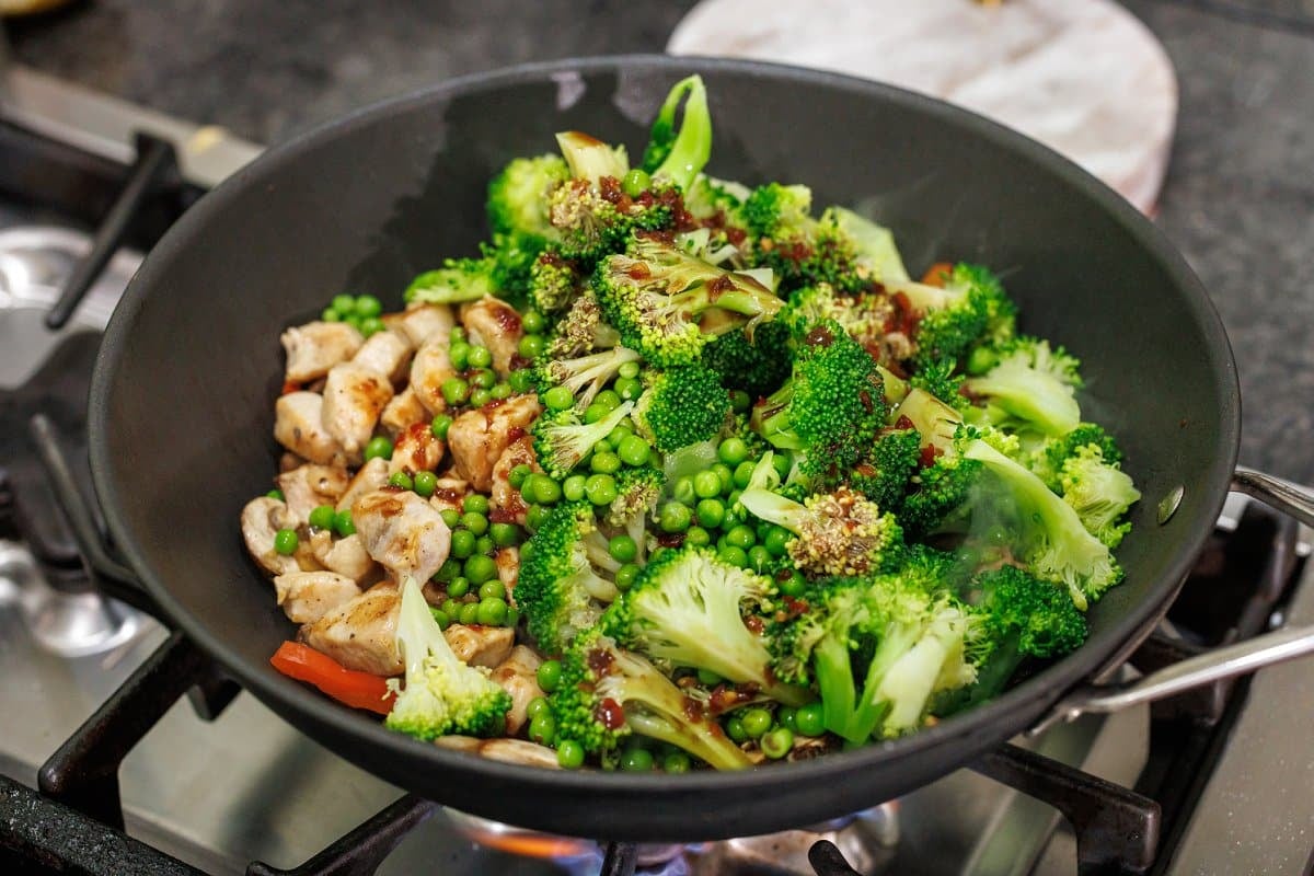 Blanched broccoli and peas added to wok.