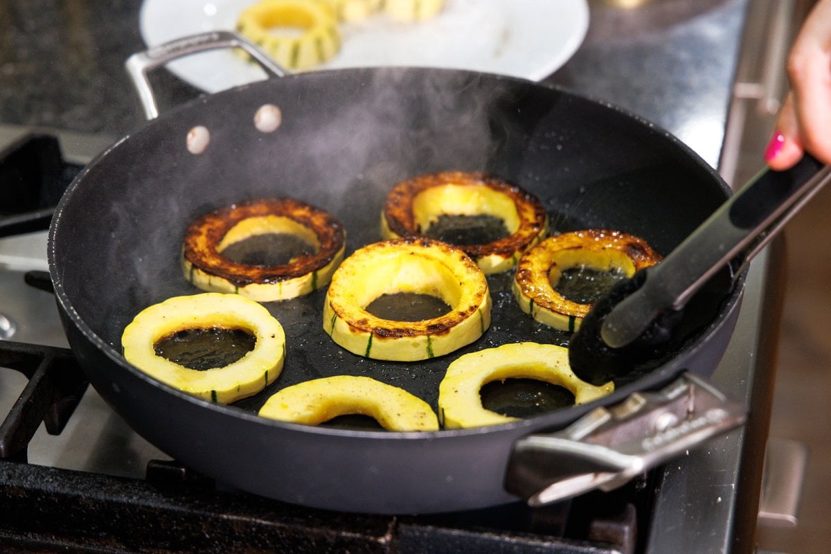 Sautéing delicata squash rings in a large skillet.
