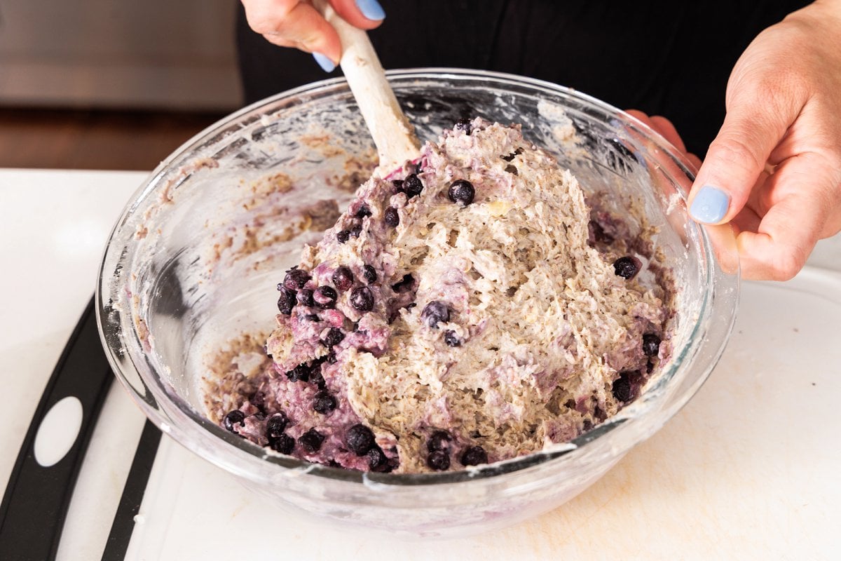 Folding blueberries into muffin batter.