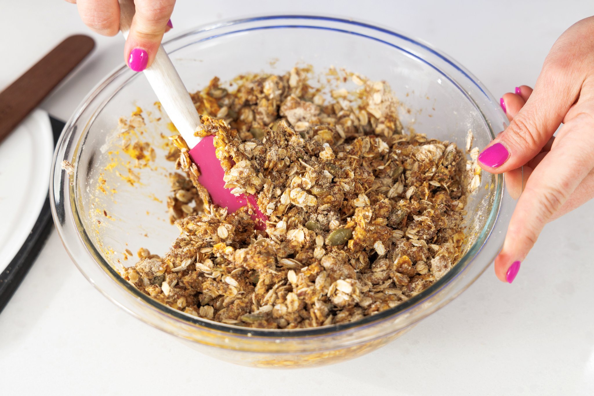 Stirring pumpkin spice granola in large glass bowl.