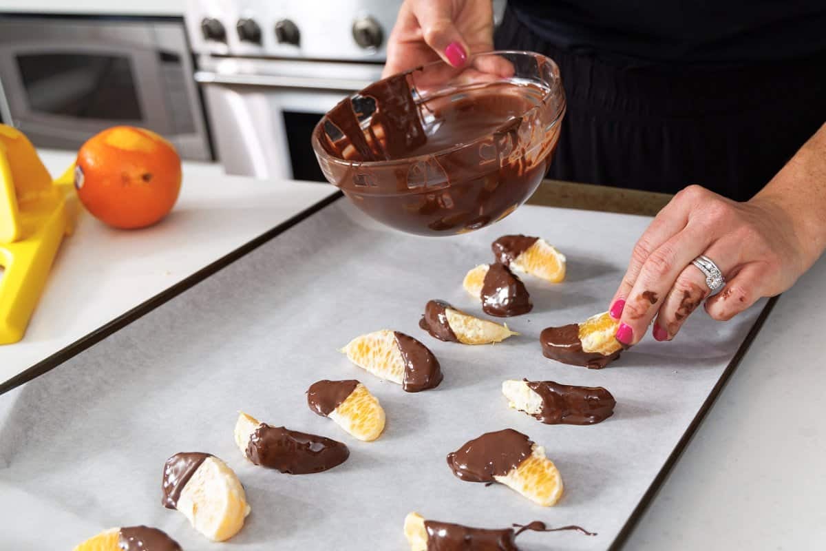Laying chocolate dipped clementine wedges on wax paper.