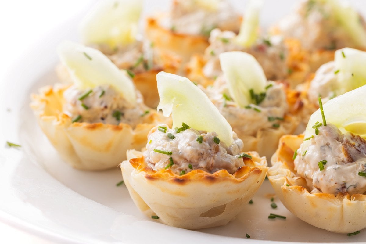 Plate full of smoked shrimp and herb spread in phyllo cups with cucumber and chive.