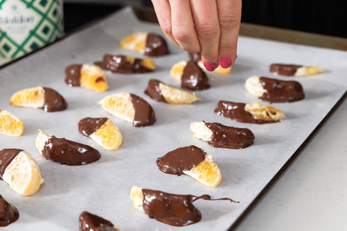 Sprinkling chocolate dipped oranges with sea salt.