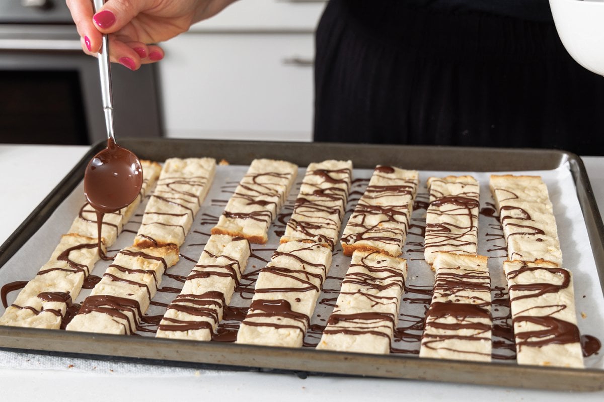 Drizzling melted chocolate over lemon shortbread cookies.