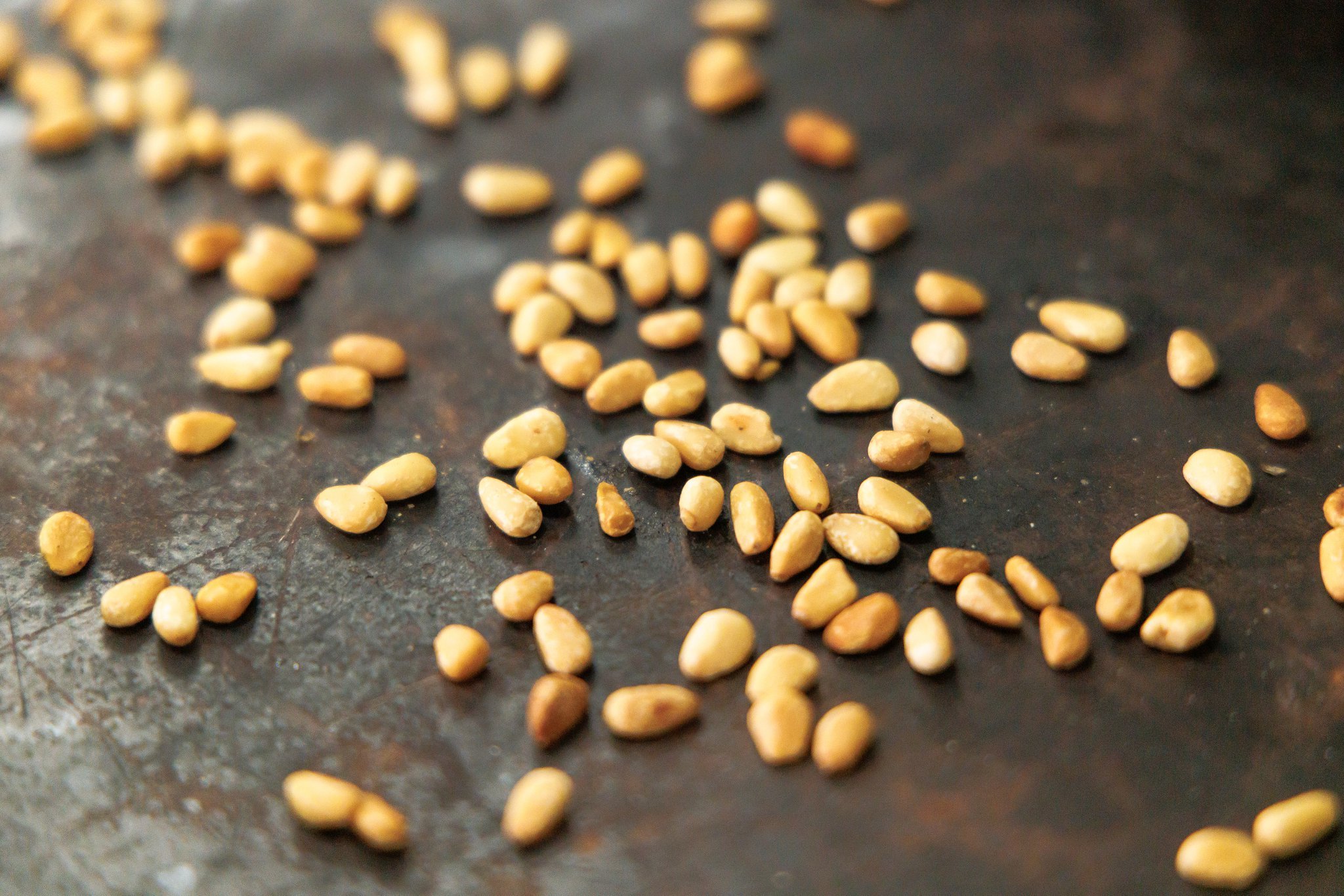 Toasting pine nuts on a dry baking sheet.