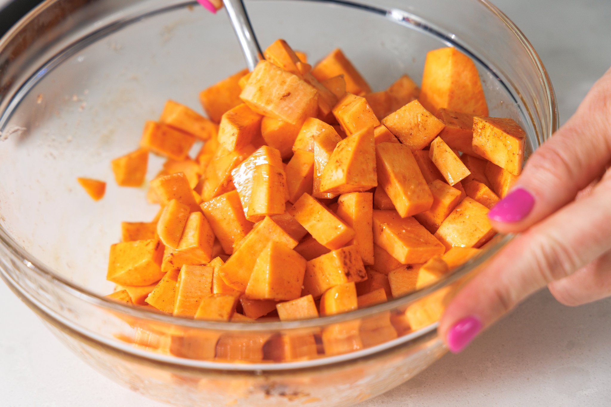 Tossing sweet potatoes in cinnamon,  oil, and maple syrup.