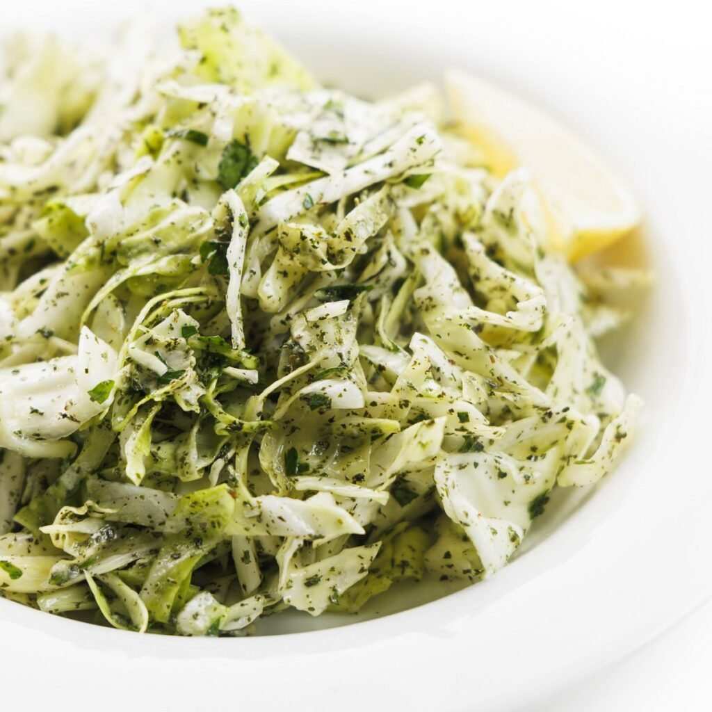 Lebanese cabbage salad up close in a shallow, white bowl.