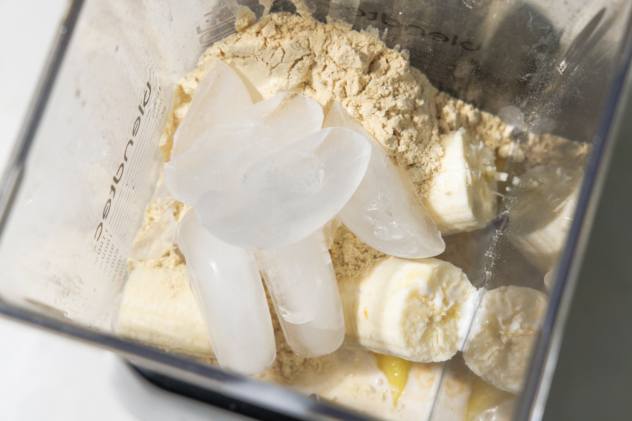 Ice added to blender with ingredients for pina colada smoothie.